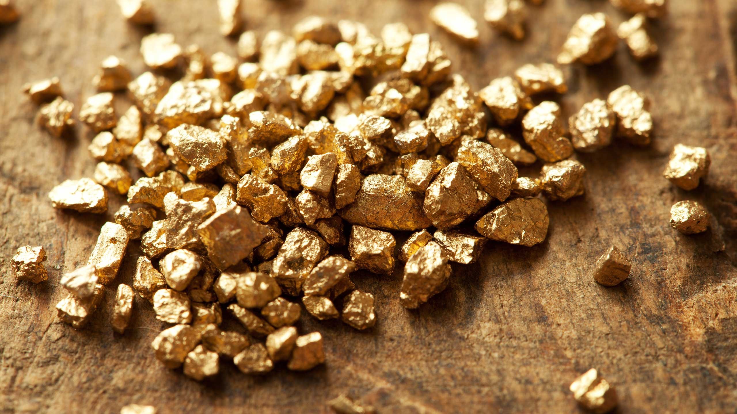 Pile of gold nuggets on wooden table
